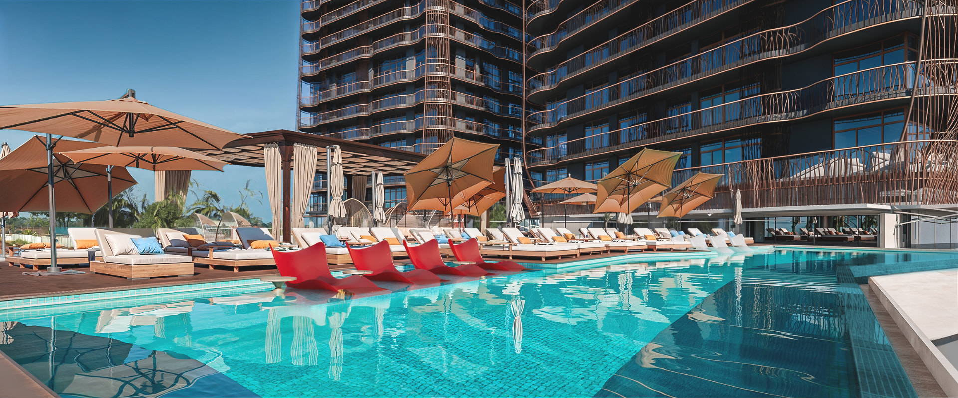 The Jabali Towers poolside deck with sun loungers and shade umbrellas at the base of the towers